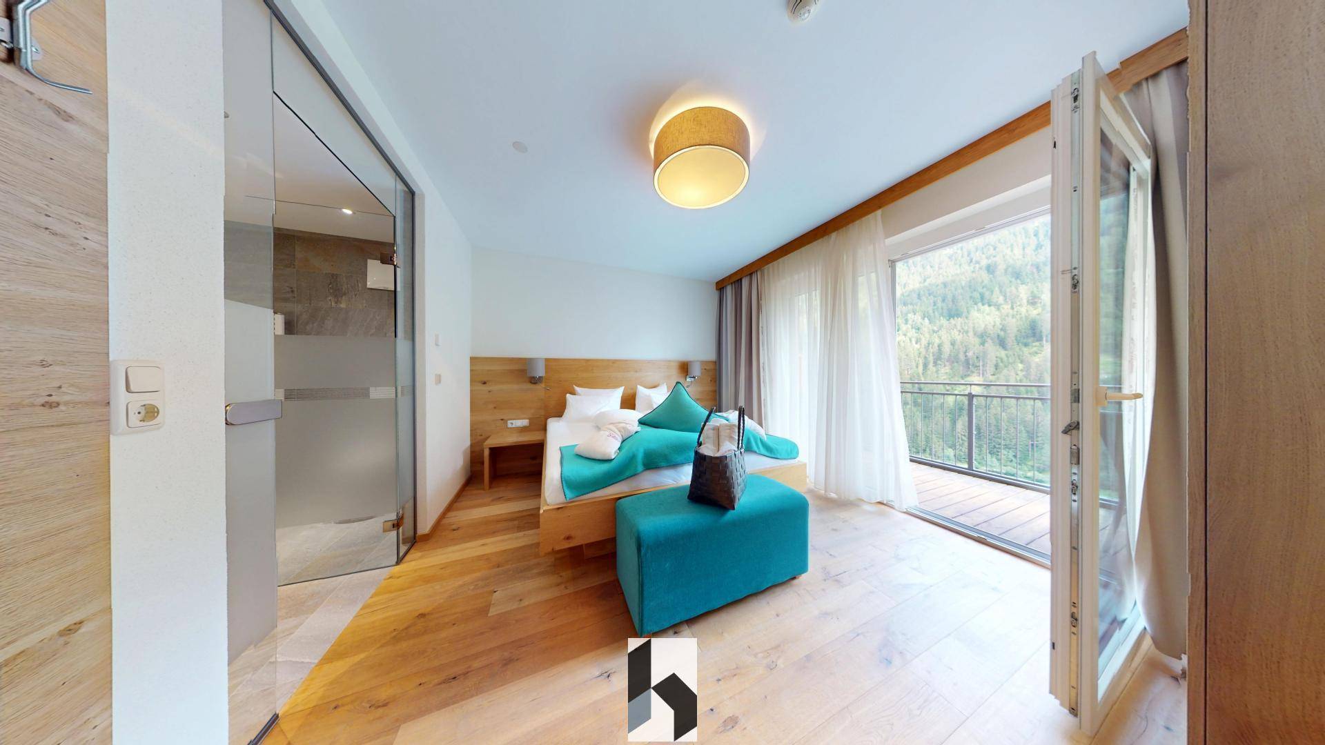 Helles Schlafzimmer mit Holzboden, Balkonzugang und angrenzendem Badezimmer, bietet einen schönen Bergblick.