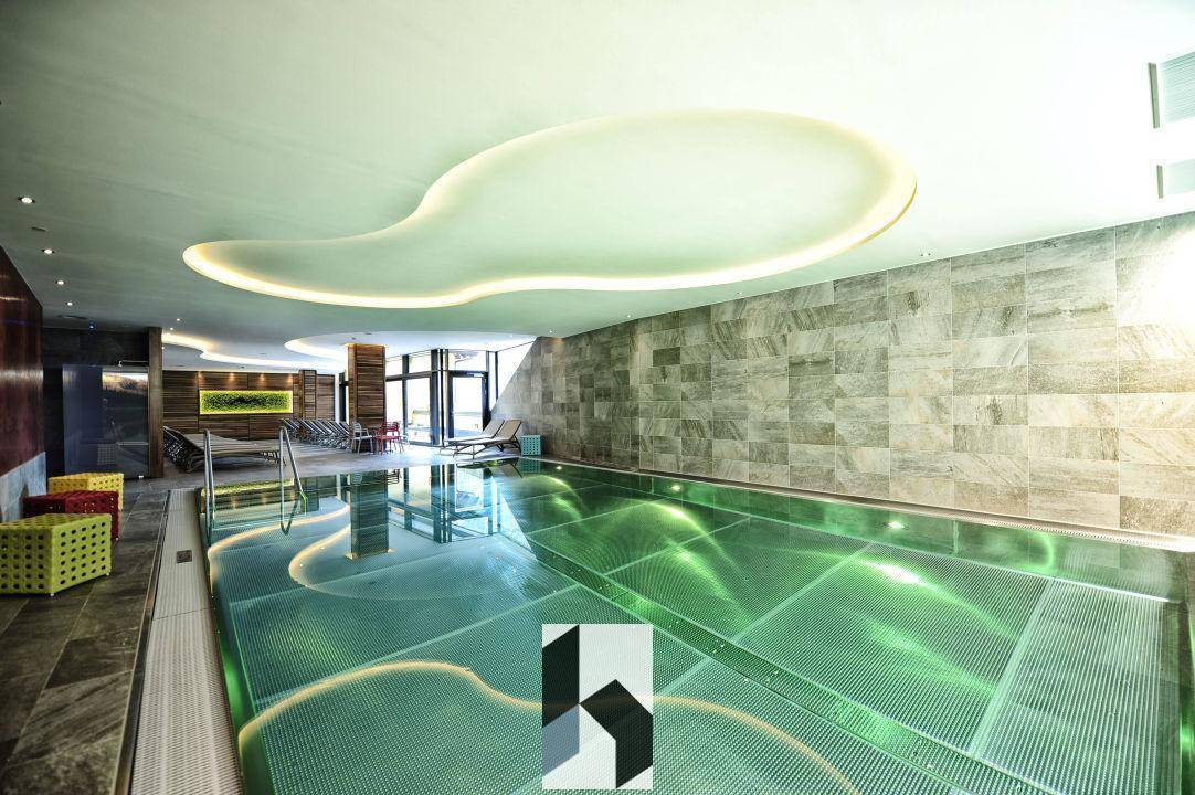 Modernes Hallenbad mit stimmungsvoller Beleuchtung und Steinwänden, Teil eines Wellnessbereichs.