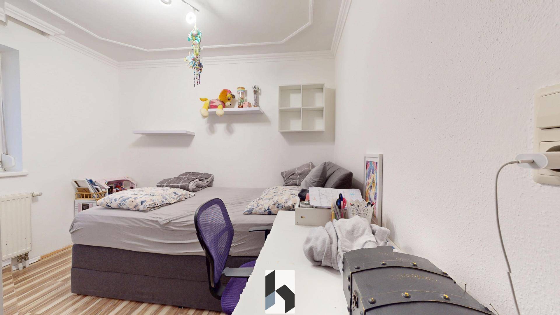 Kinderzimmer mit Einzelbett, Schreibtisch und verspielter, bunter Dekoration an der Decke.