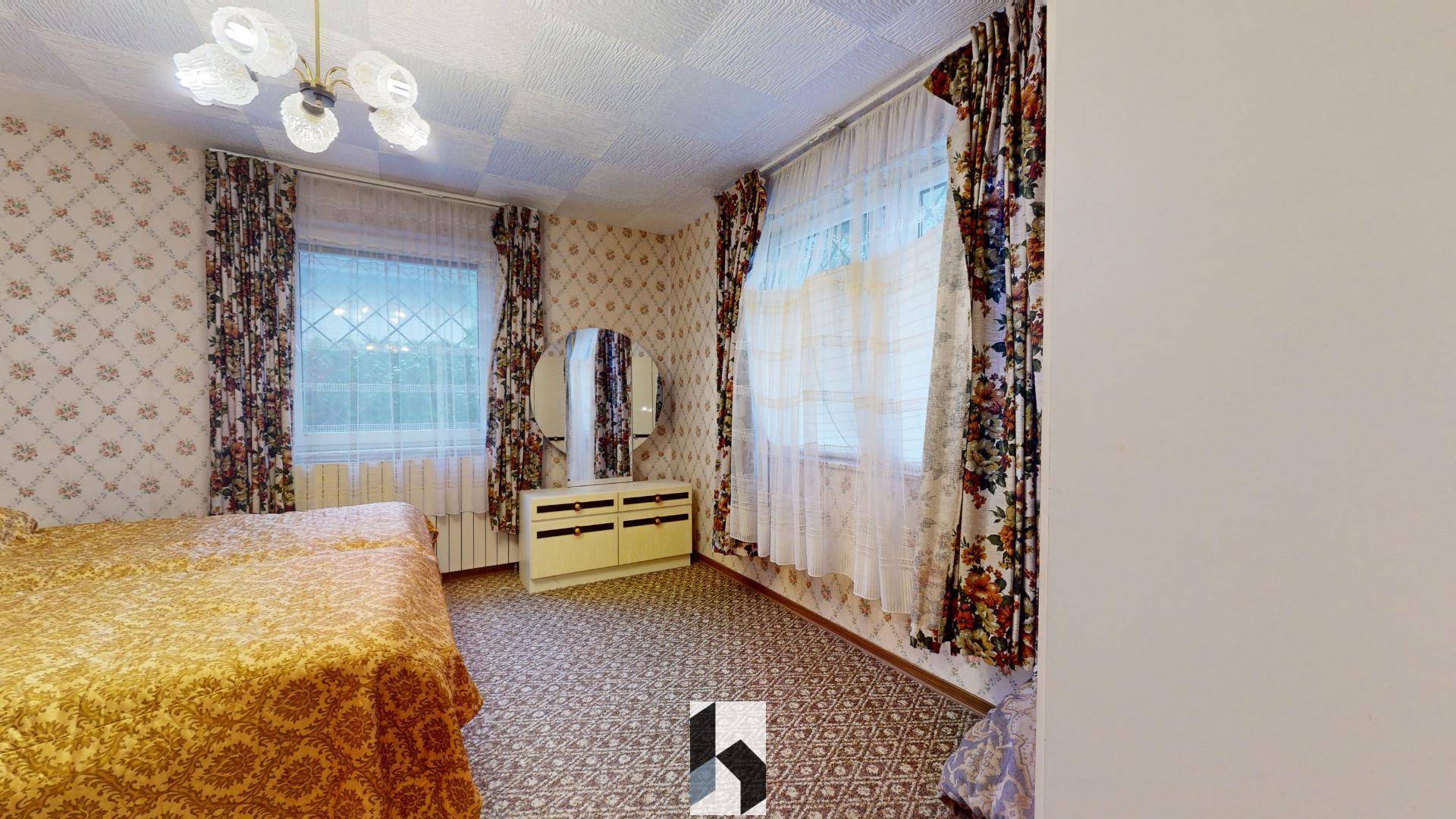 Schlafzimmer im Retro-Stil mit gemusterter Tapete, Teppichboden und einem Schminktisch.