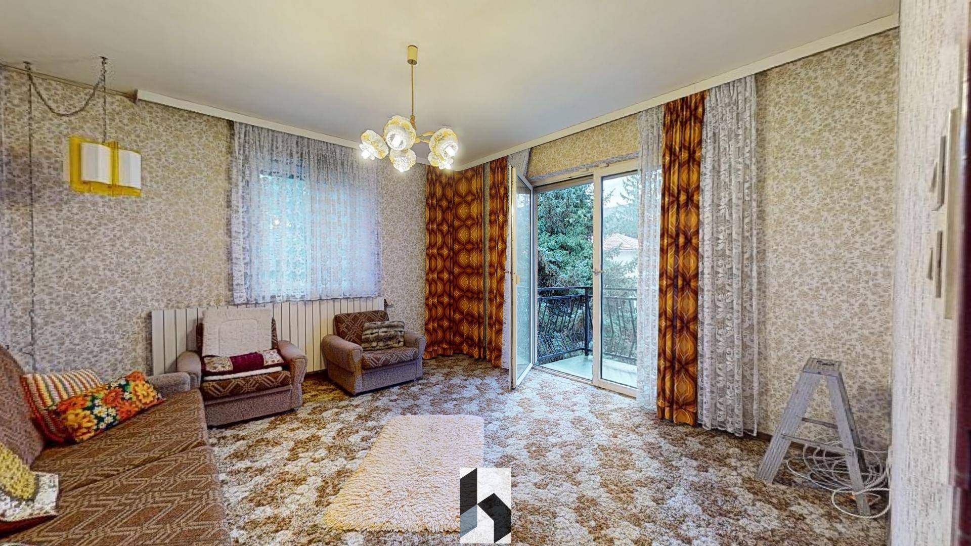 Wohnzimmer im Vintage-Stil mit gemusterter Tapete, Teppichboden und Zugang zum Balkon.