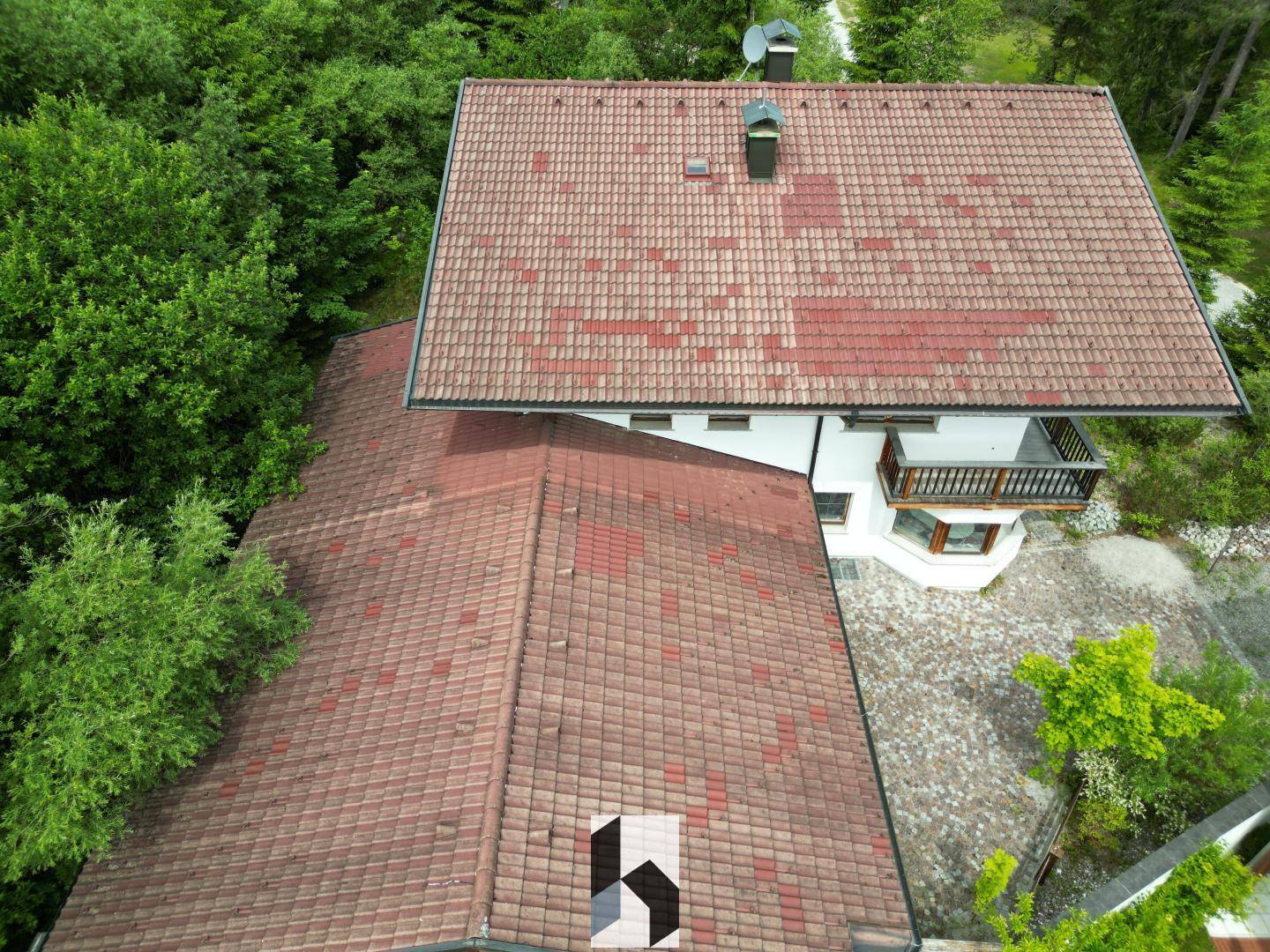Dachansicht des Hauses mit traditionellen roten Ziegeln, umgeben von üppiger Vegetation.