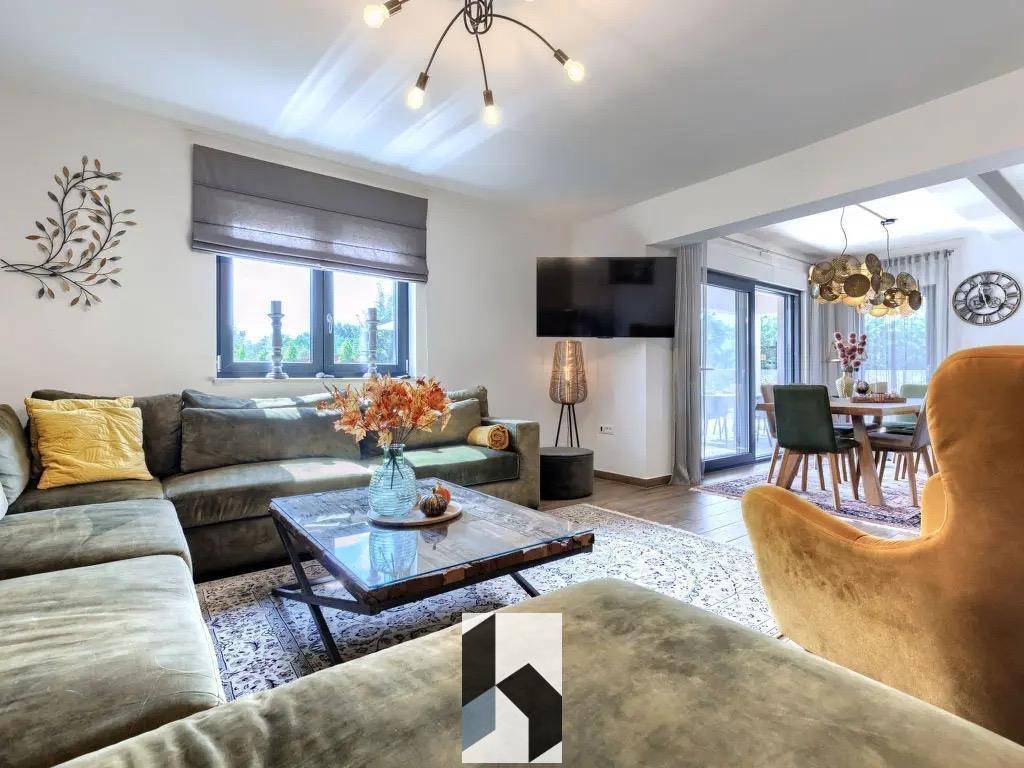 Gemütlicher Wohnbereich mit großem Sofa, Teppich und offenem Übergang zum Esszimmer.
