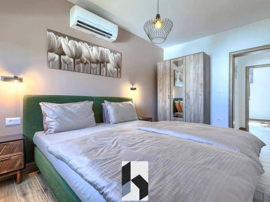 Helles Schlafzimmer mit Doppelbett, Holzschrank und Klimaanlage für angenehme Nächte.