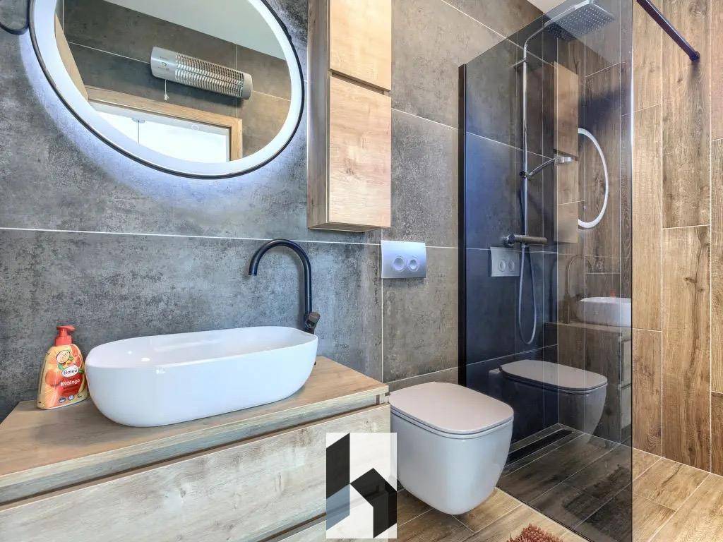 Modernes Badezimmer mit begehbarer Dusche, Aufsatzwaschbecken und dunklen Fliesen.