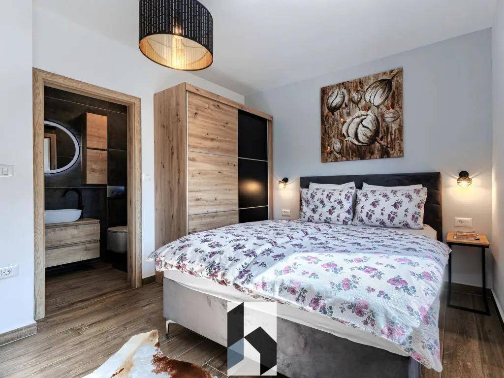 Gemütliches Schlafzimmer mit Doppelbett, Holzboden und direktem Zugang zum Badezimmer.