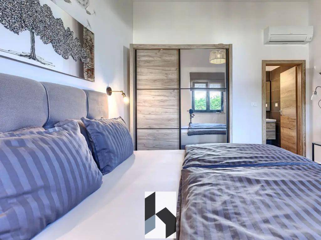 Komfortables Schlafzimmer mit Doppelbett, Spiegelschrank und Zugang zu einem weiteren Raum.