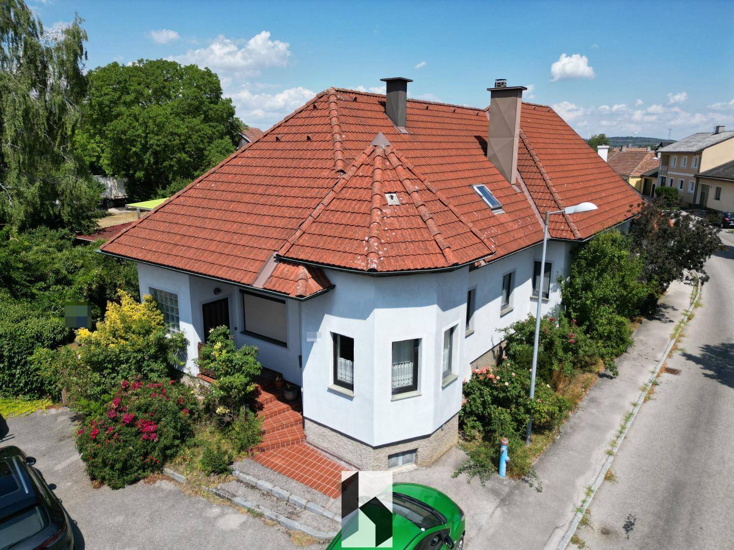 Ansicht des Hauses von oben mit rotem Ziegeldach, weißer Fassade und umliegender Nachbarschaft.