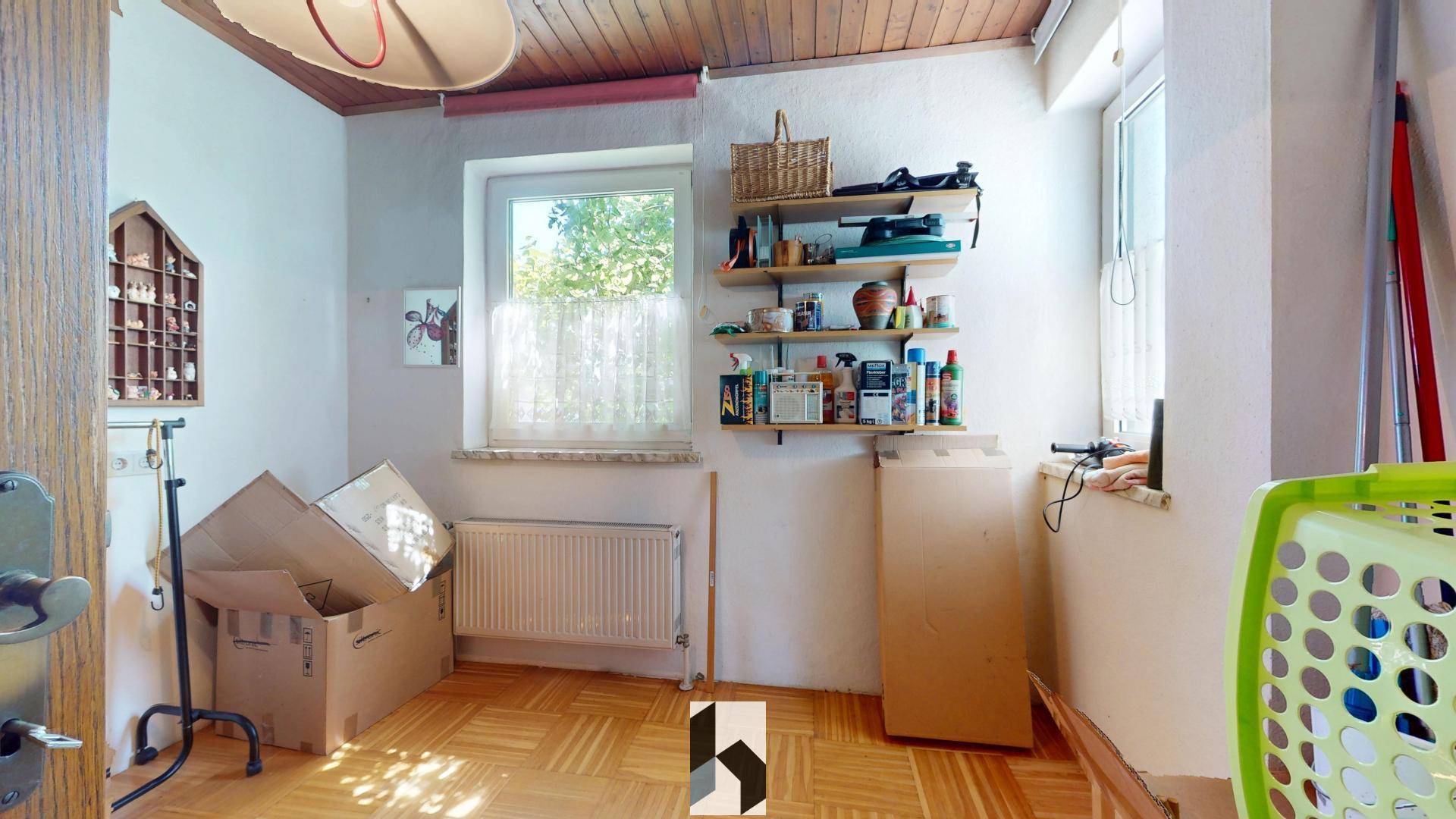 Praktischer Hauswirtschaftsraum mit Fenster, Heizkörper und Regalen für Lagerung und Organisation.
