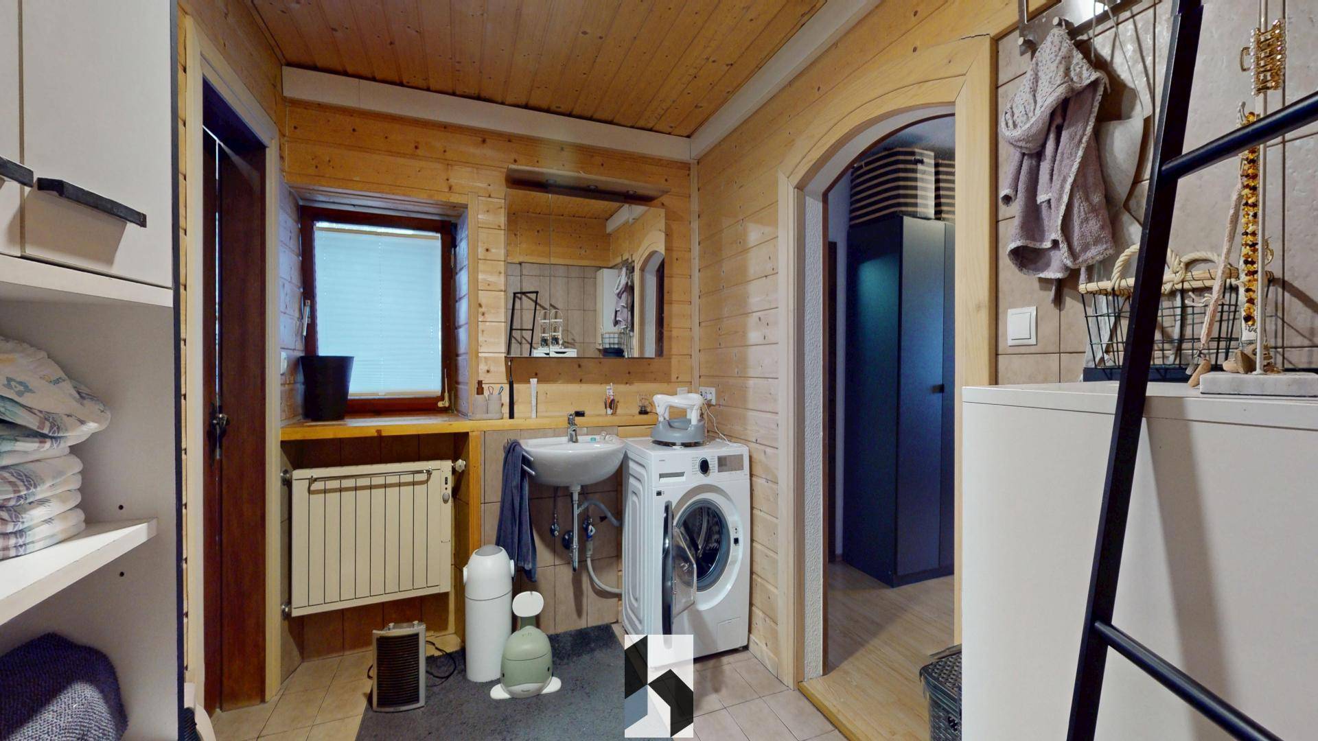 Rustikales Badezimmer mit Holzverkleidung, Waschbecken, Waschmaschine und Fenster.