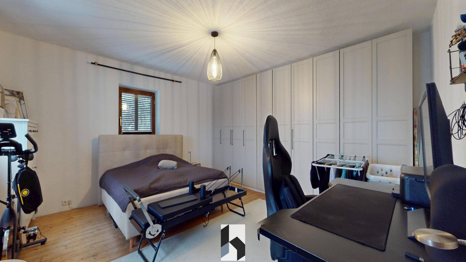 Helles Schlafzimmer mit großem Kleiderschrank, Doppelbett und Arbeitsbereich.