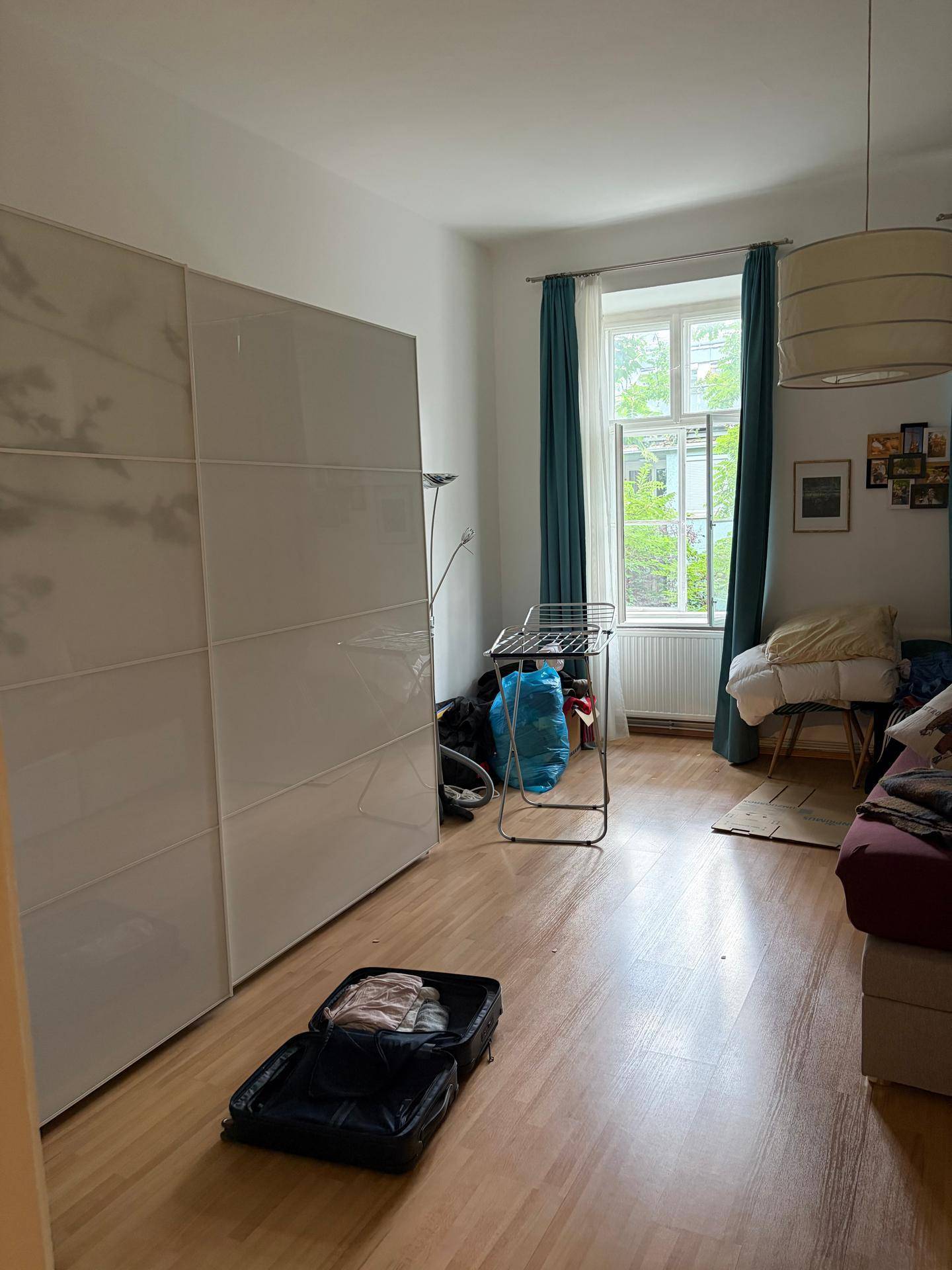 Schlafzimmer mit großem Kleiderschrank, Holzboden und Fenster mit Blick ins Grüne.