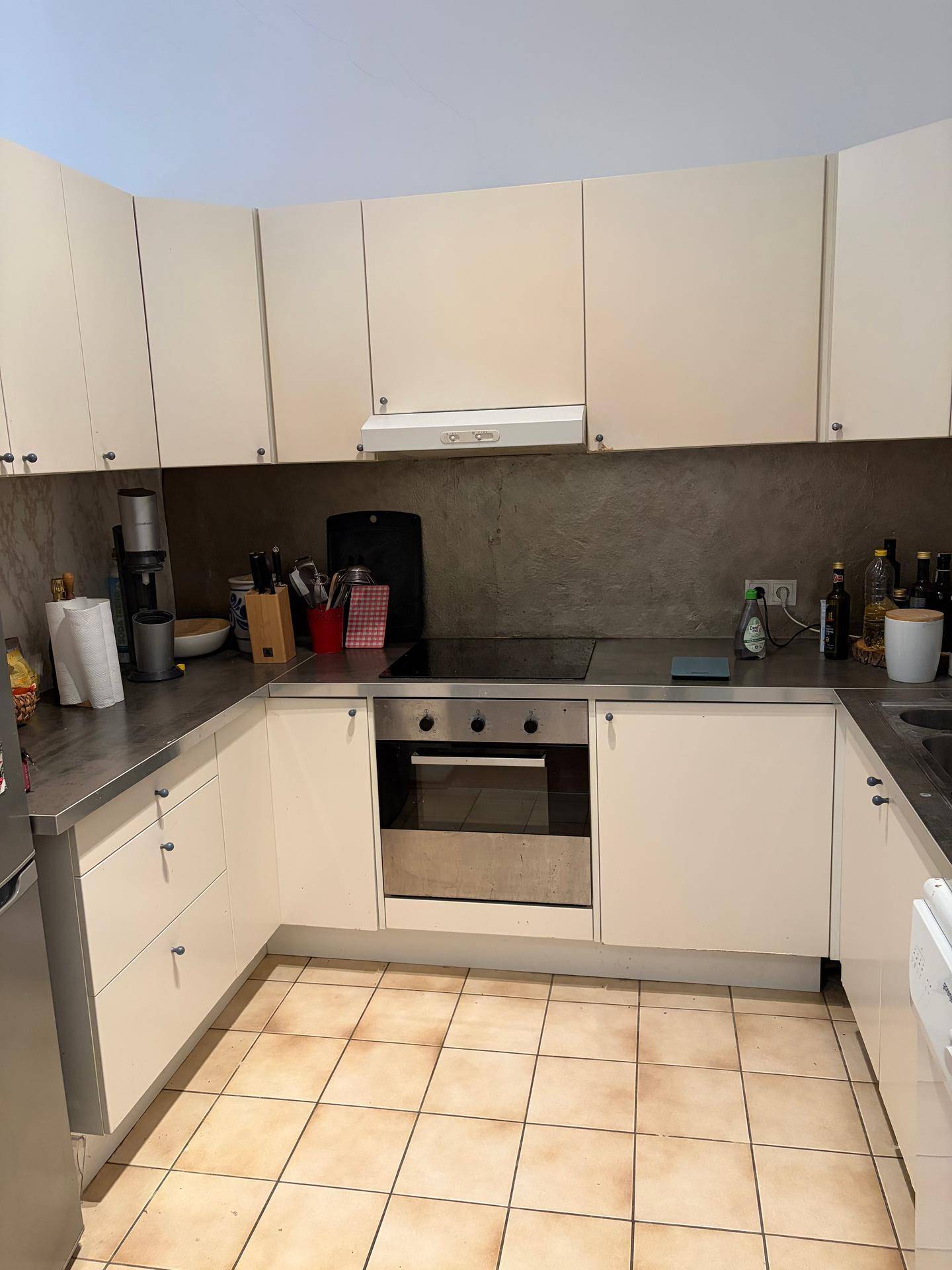 Funktionale Küche mit hellen Schränken, dunklen Arbeitsplatten und integriertem Backofen und Kochfeld.