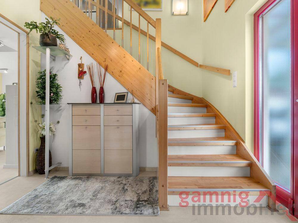 Heller Eingangsbereich mit Holztreppe und modernem Sideboard.