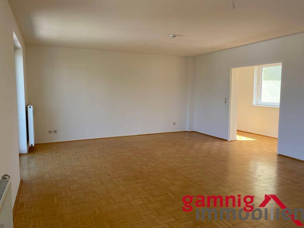 Geräumiges Wohnzimmer mit hellem Parkettboden und weiß gestrichenen Wänden, bereit zur Einrichtung.