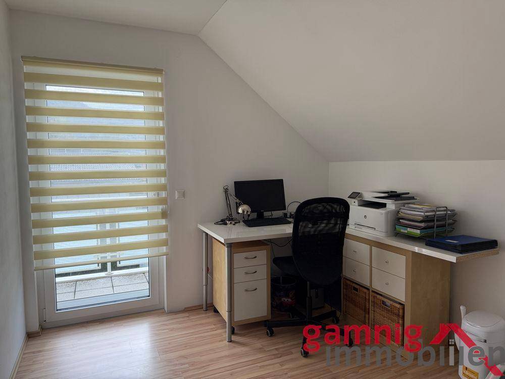 Helles Arbeitszimmer im Dachgeschoss mit Schreibtisch und Fenster.