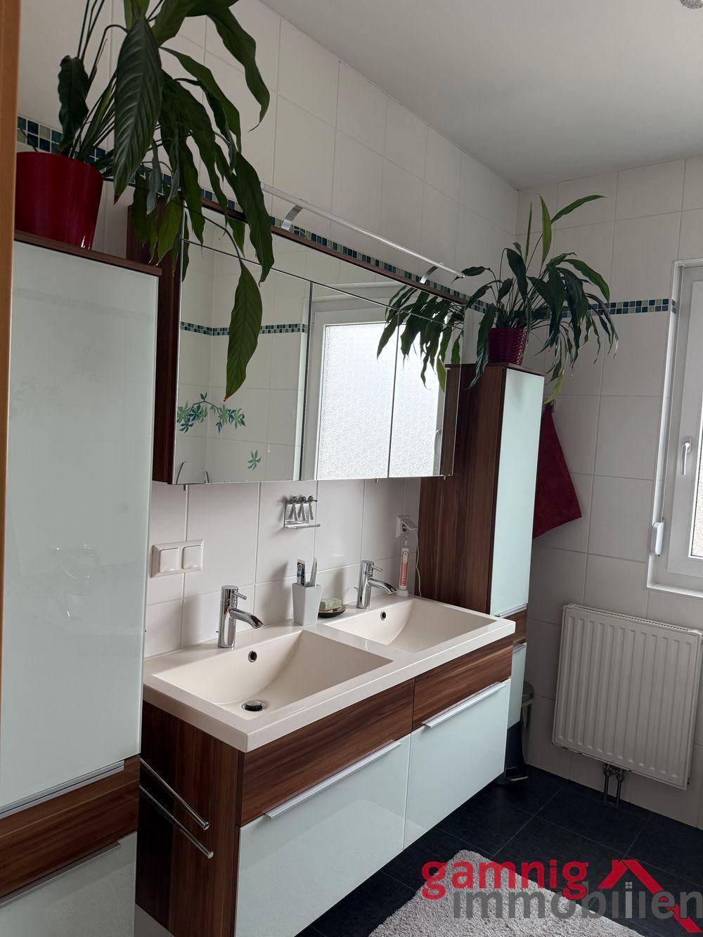 Badezimmer mit Doppelwaschbecken, Spiegelschrank und Pflanzen.