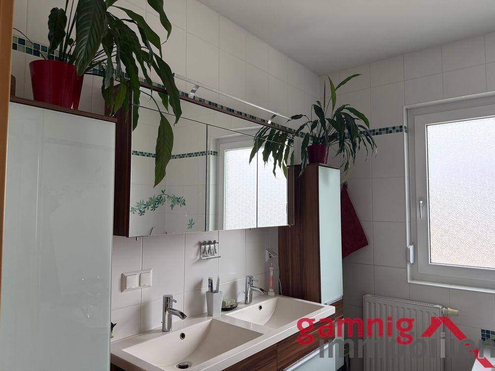Badezimmer mit Doppelwaschbecken, Spiegelschrank und Pflanzen.