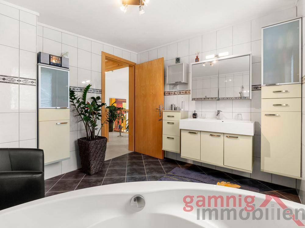 Geräumiges Badezimmer mit Badewanne, Waschtisch und viel Stauraum.