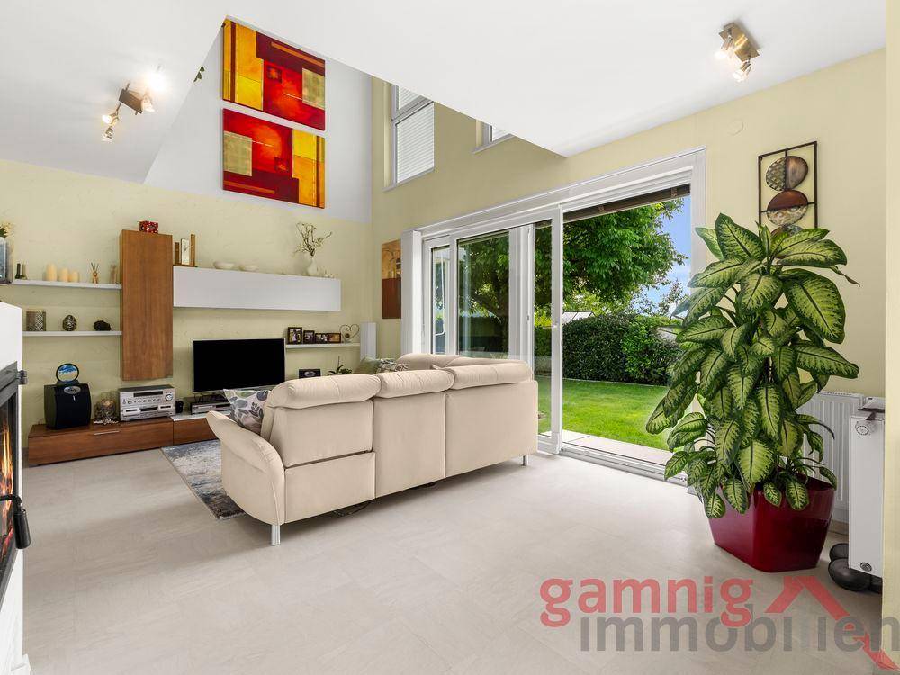 Geräumiges Wohnzimmer mit Kamin, Zugang zum Garten und hohen Decken.