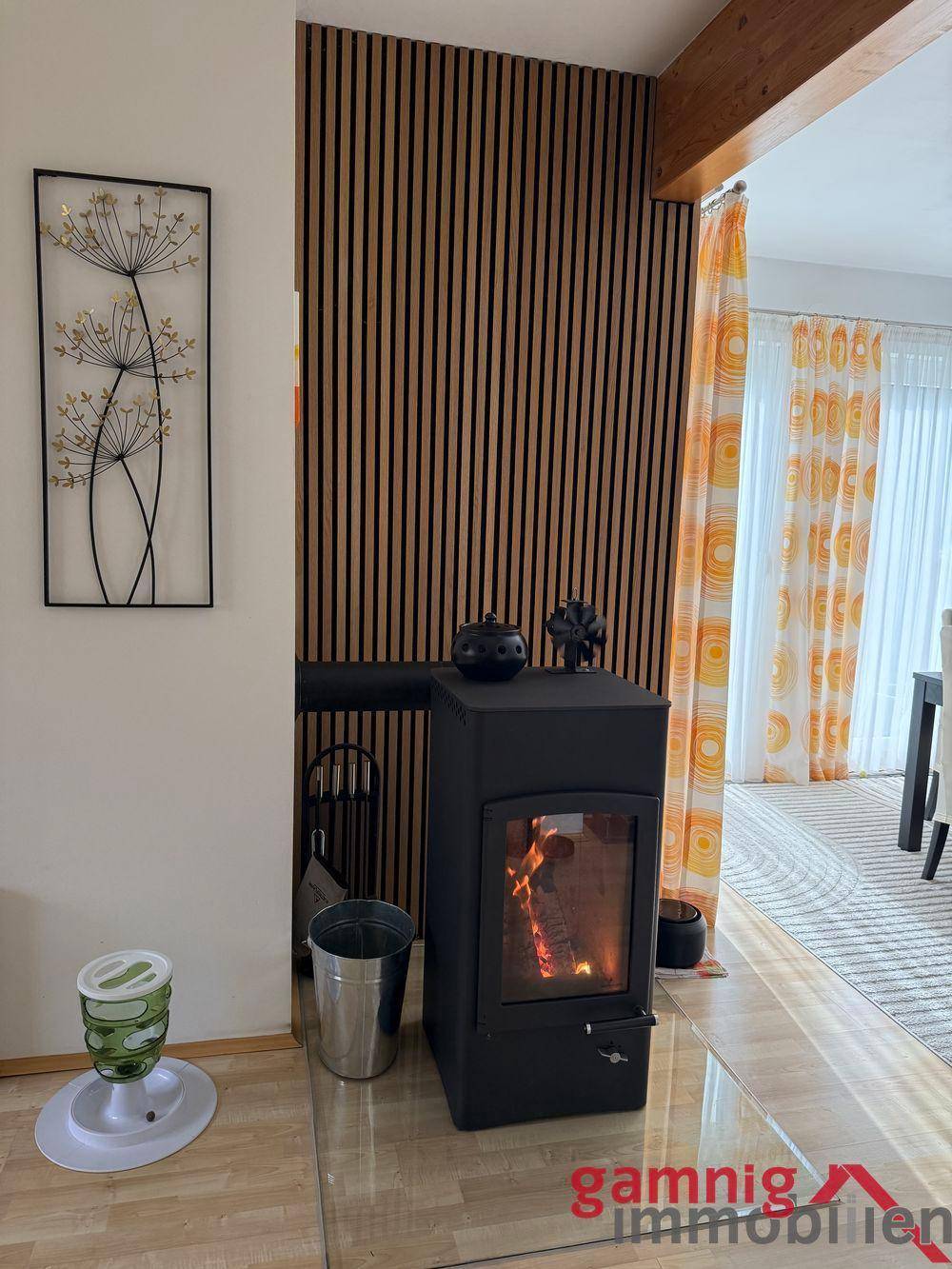 Moderner Holzofen im Wohnbereich mit dekorativer Holzlamellenwand.