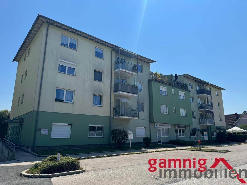 Ansicht eines modernen Wohngebäudes mit grüner Fassade, Balkonen und großen Fenstern.