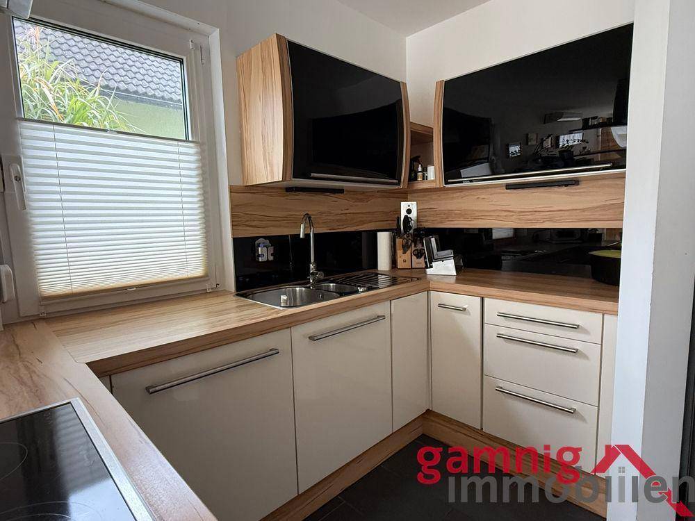 Helle Küche mit Holz-Arbeitsplatte, Spüle und modernen Hängeschränken.