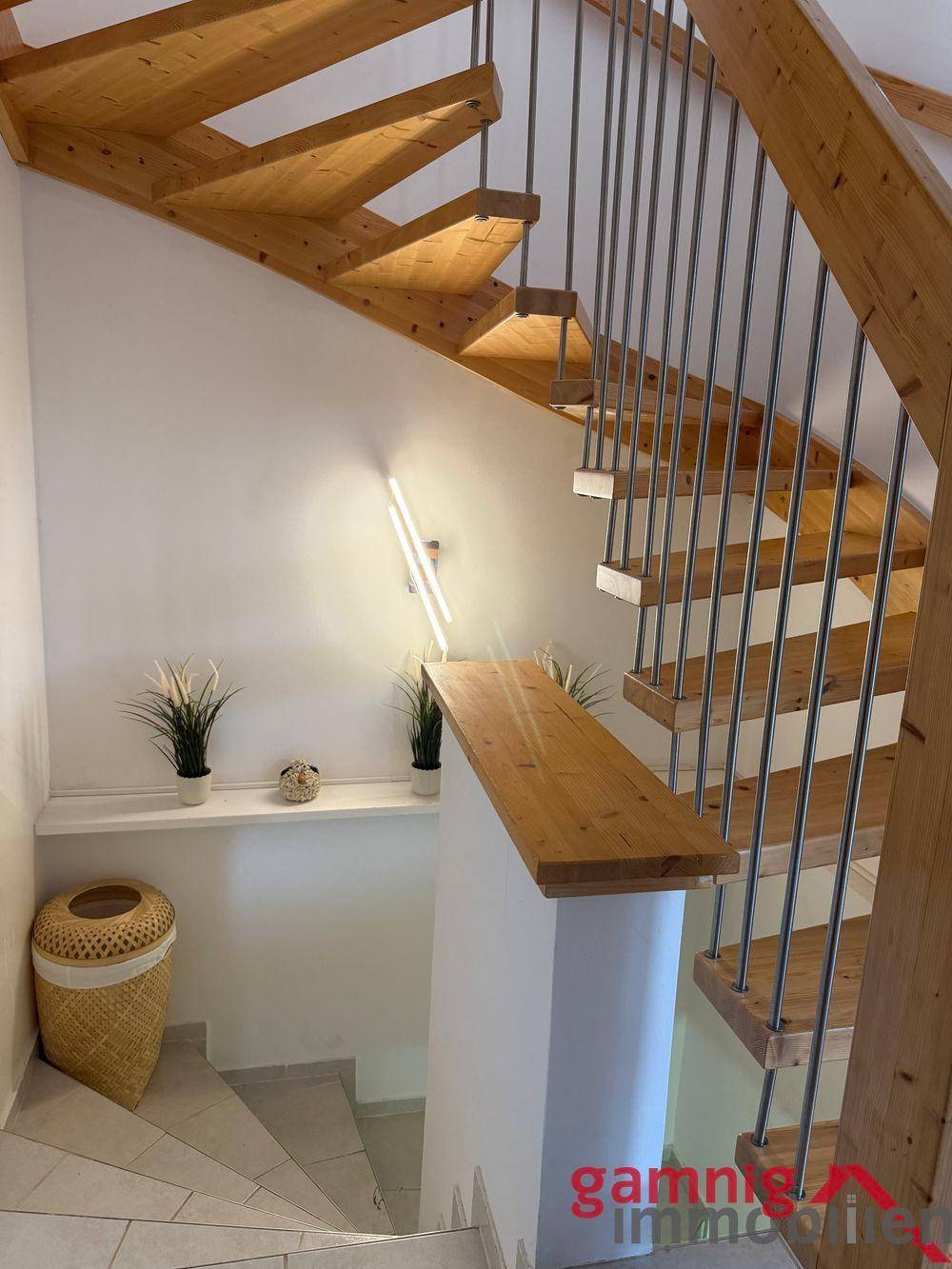 Moderne Holztreppe mit schwebenden Stufen und Metallgeländer in einem hellen Treppenhaus.