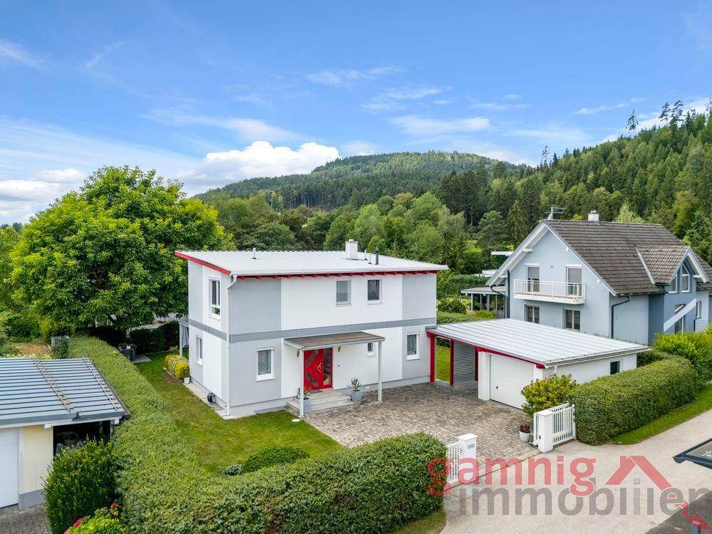 Luftaufnahme des modernen Einfamilienhauses mit Carport und gepflegtem Garten.