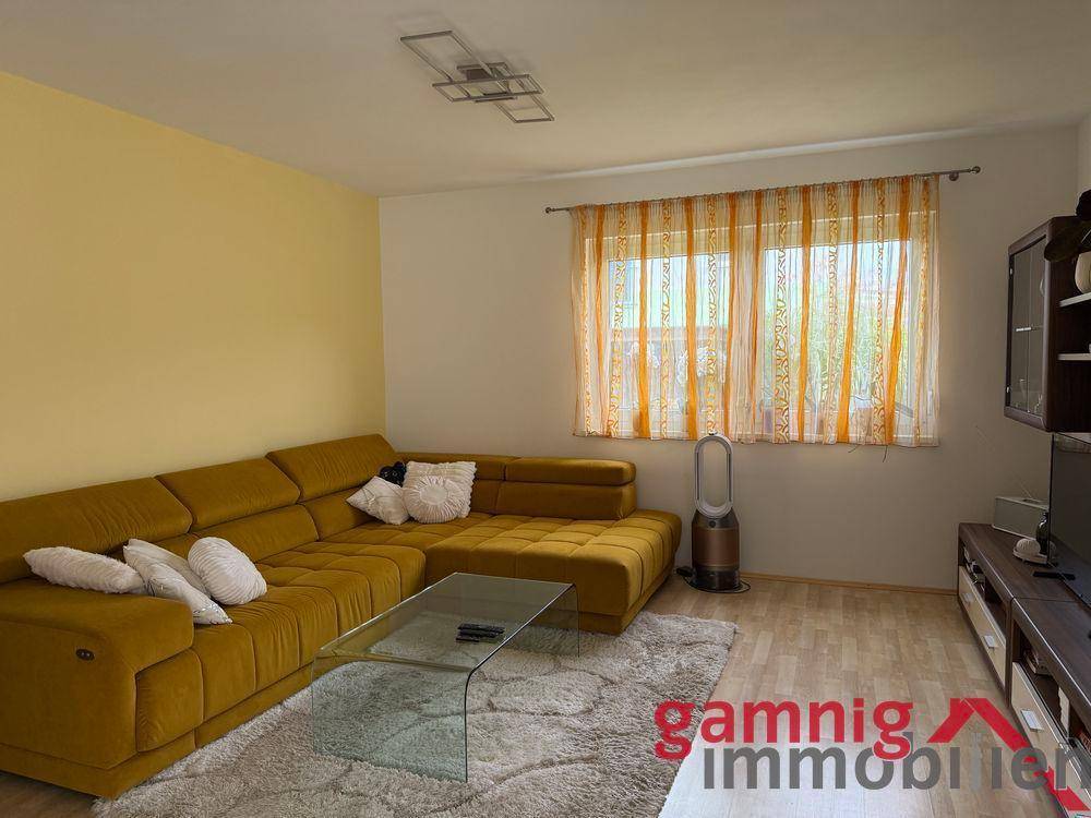 Gemütliches Wohnzimmer mit großem gelbem Ecksofa und hellem Parkettboden.
