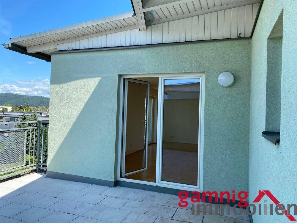 Zugang zur sonnigen Terrasse durch eine große Glastür, die viel Licht in den Innenraum lässt.