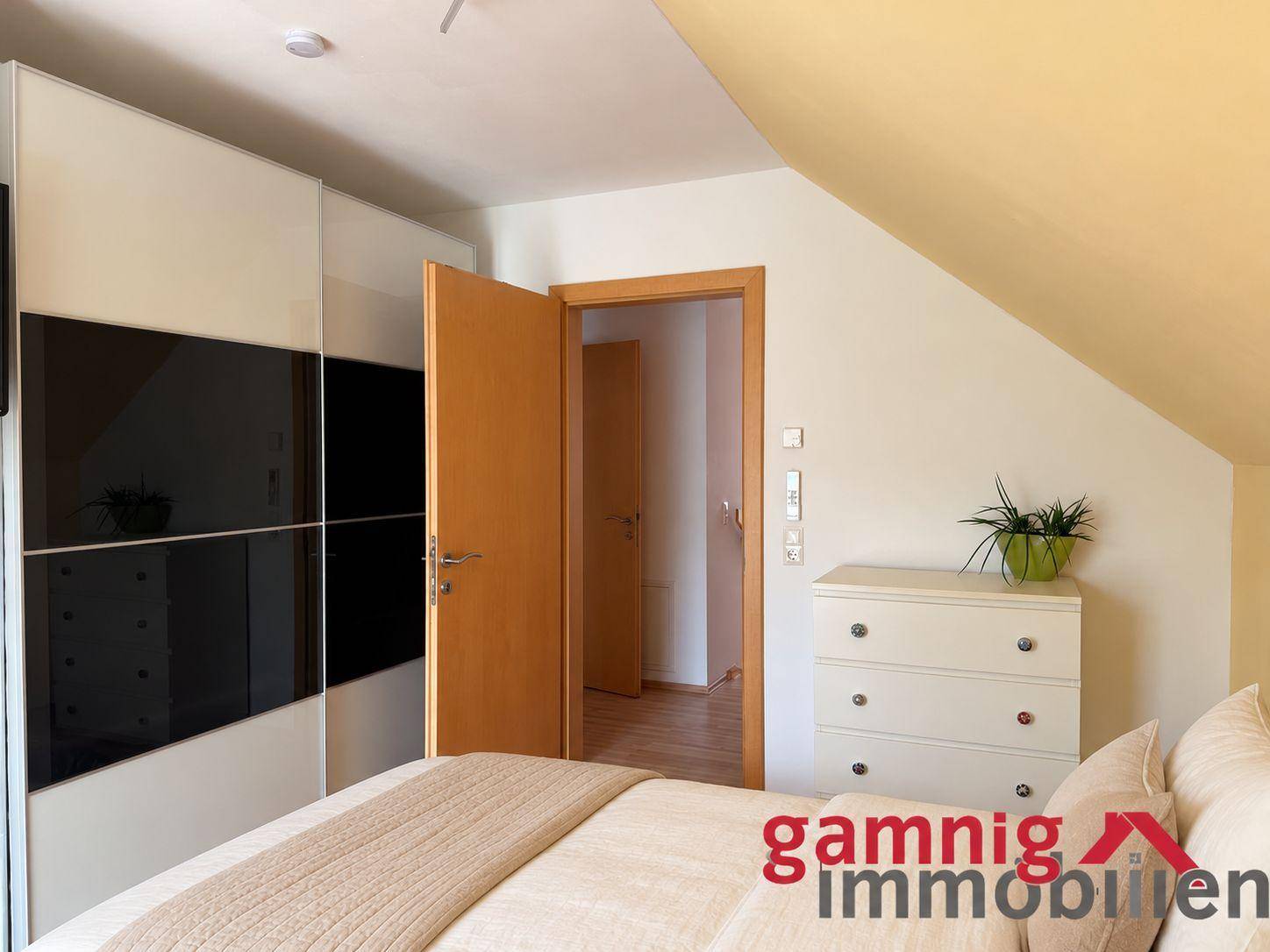 Schlafzimmer im Dachgeschoss mit Schräge, großem Kleiderschrank und Holzboden.