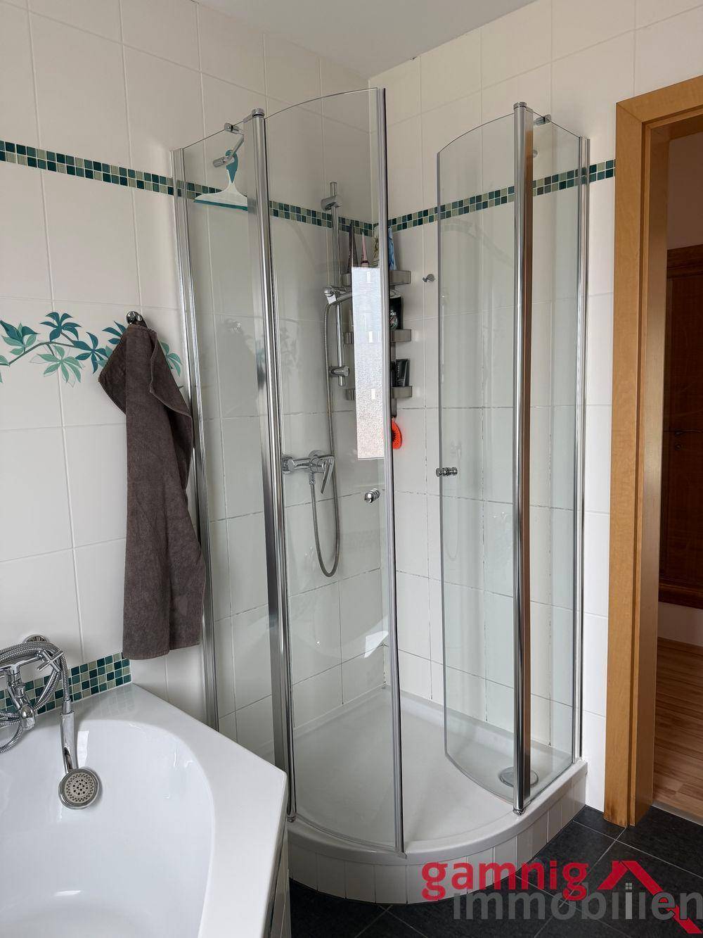 Badezimmer mit Duschkabine und Teil einer Badewanne.