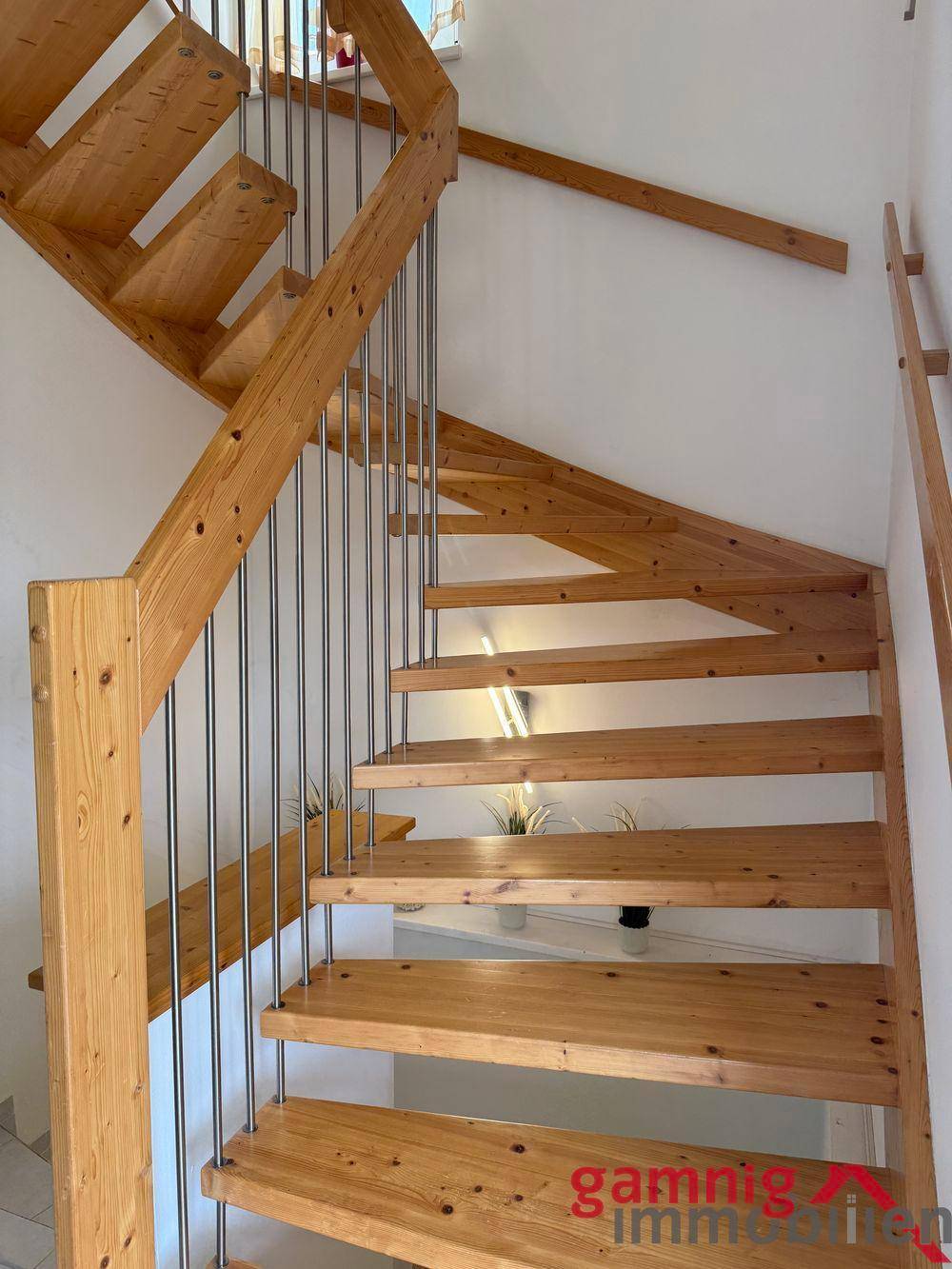 Helle Holztreppe mit Metallgeländer, die in das obere Stockwerk führt.
