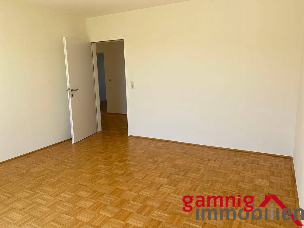 Schlafzimmer mit klassischem Parkettboden und weiß gestrichenen Wänden, bietet Zugang zu weiteren Räumen.