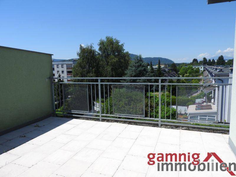 Geräumige Dachterrasse mit Fliesenboden und weitem Blick über die Umgebung und Berge.