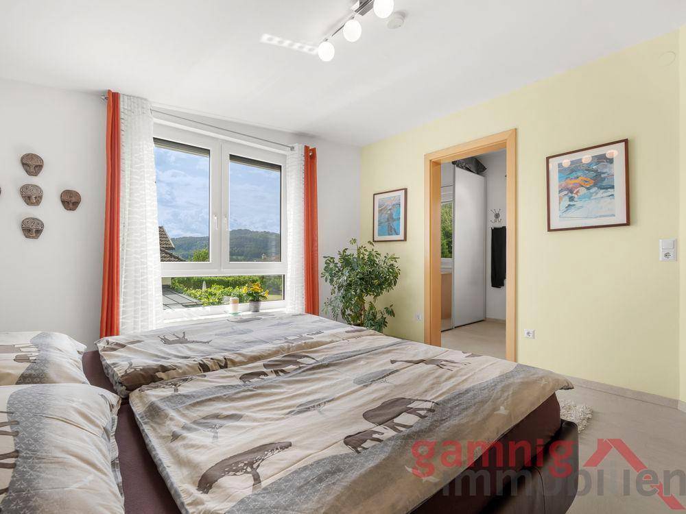 Schlafzimmer mit Doppelbett, großen Fenstern und Blick ins Grüne.