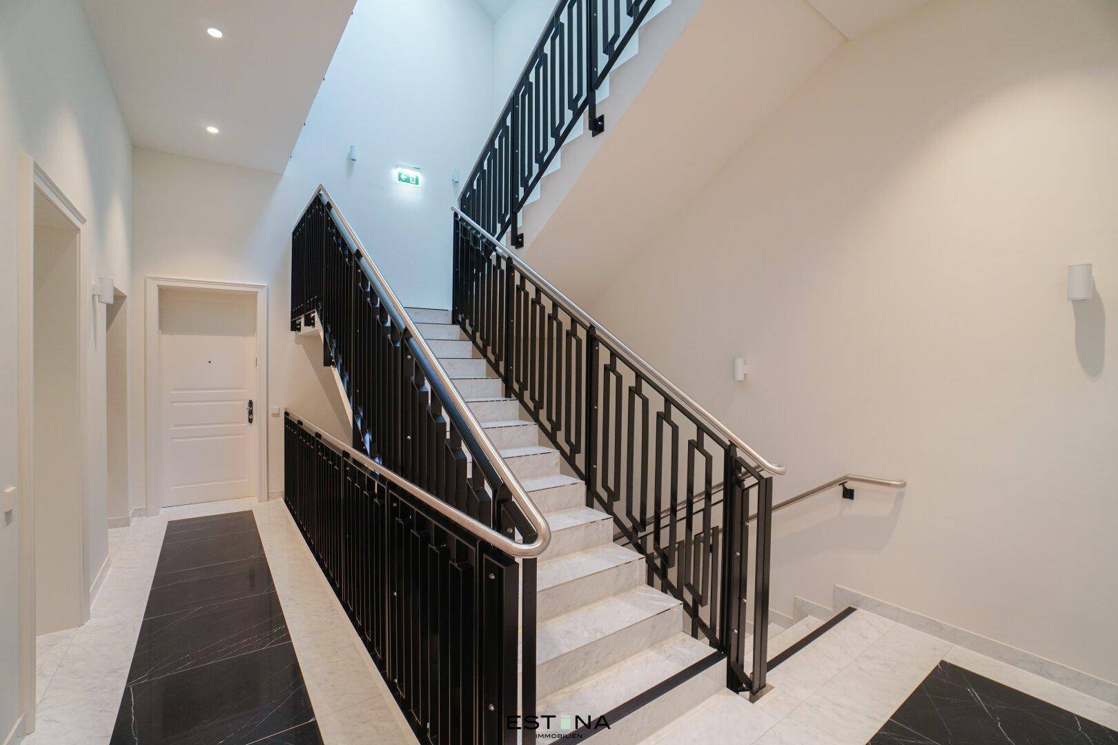 Elegantes Treppenhaus mit Marmorstufen, schmiedeeisernem Geländer und klassischem Design.