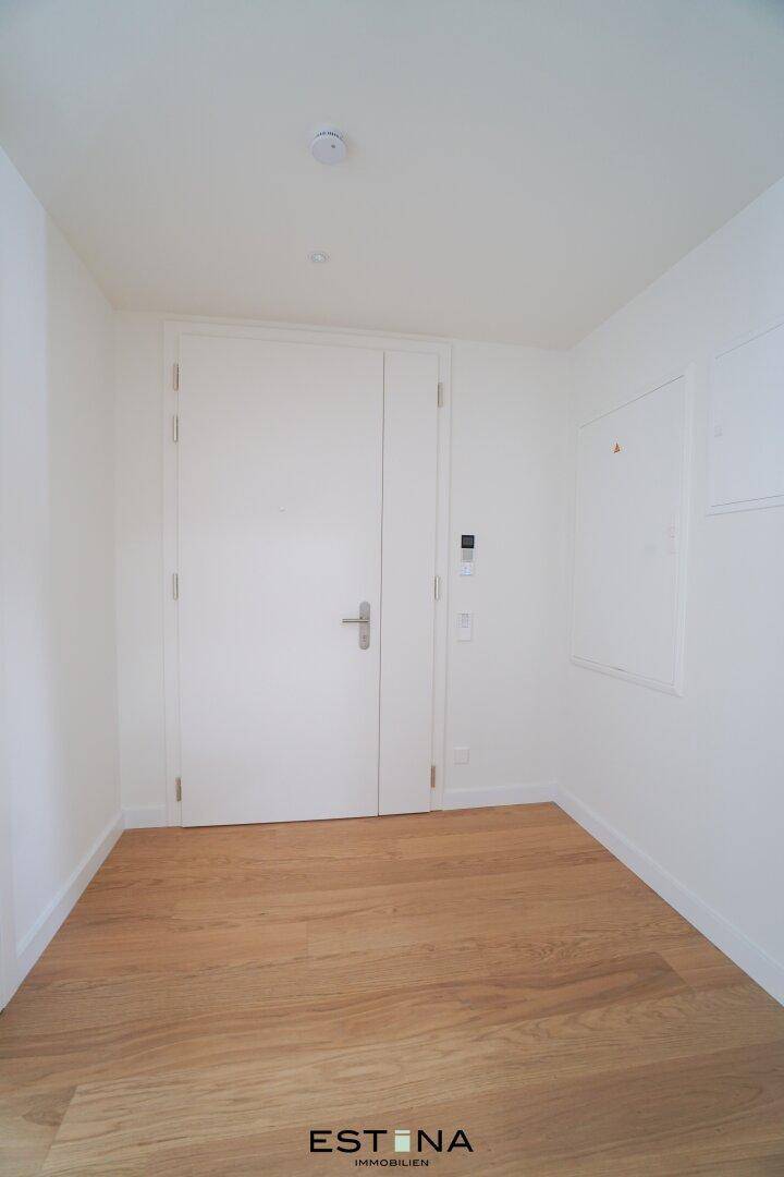 Heller Eingangsbereich mit Holzboden und weißer Doppeltür, der einen modernen Eindruck vermittelt.
