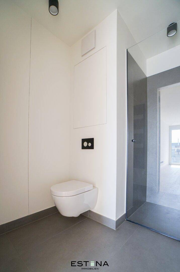 Separate Toilette mit wandhängendem WC und modernen grauen Bodenfliesen.