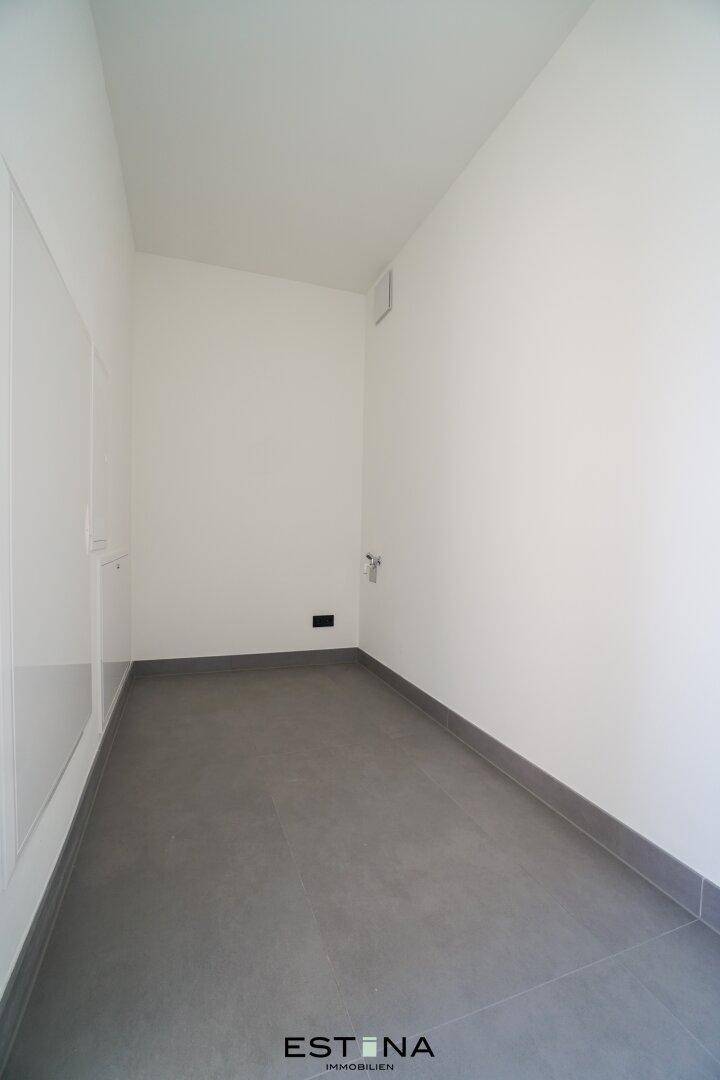 Leerer Raum mit grauen Fliesen, ideal als Abstellraum oder Waschküche nutzbar.