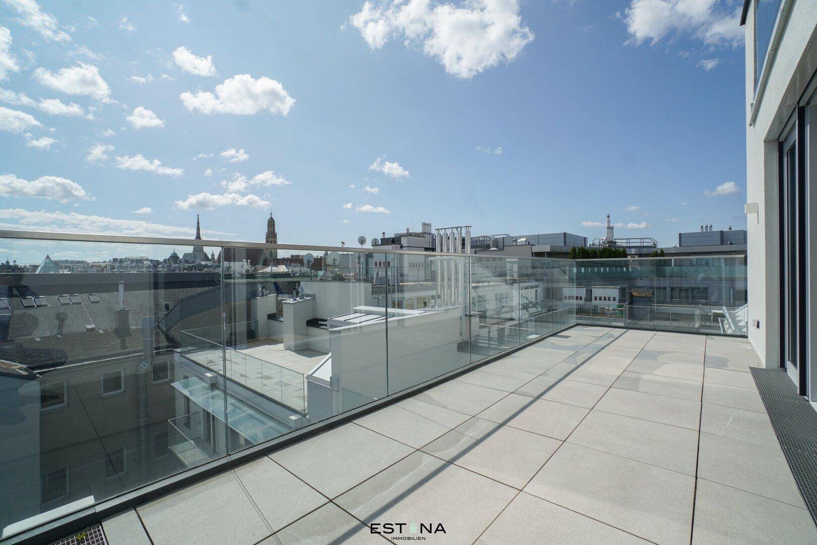 Moderne Dachterrasse mit Glasgeländer und weitem Blick über die Stadtlandschaft.