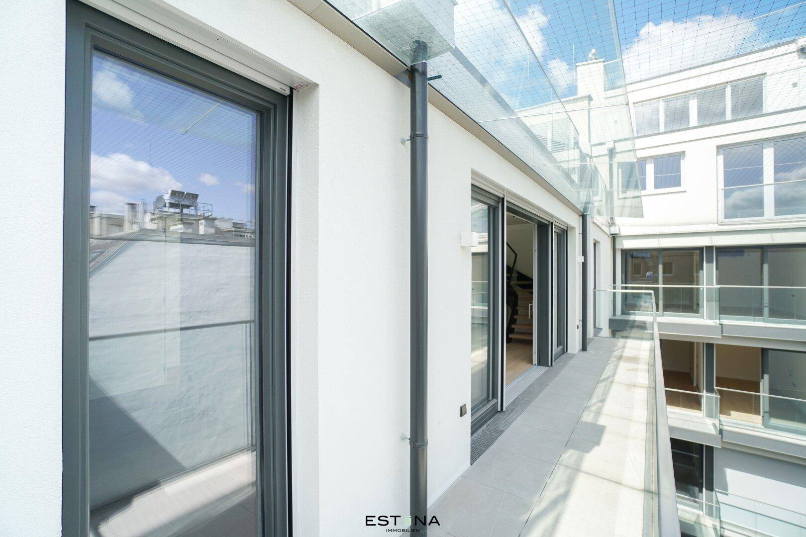 Schmaler Balkon mit Glasüberdachung und Blick auf die Nachbargebäude.