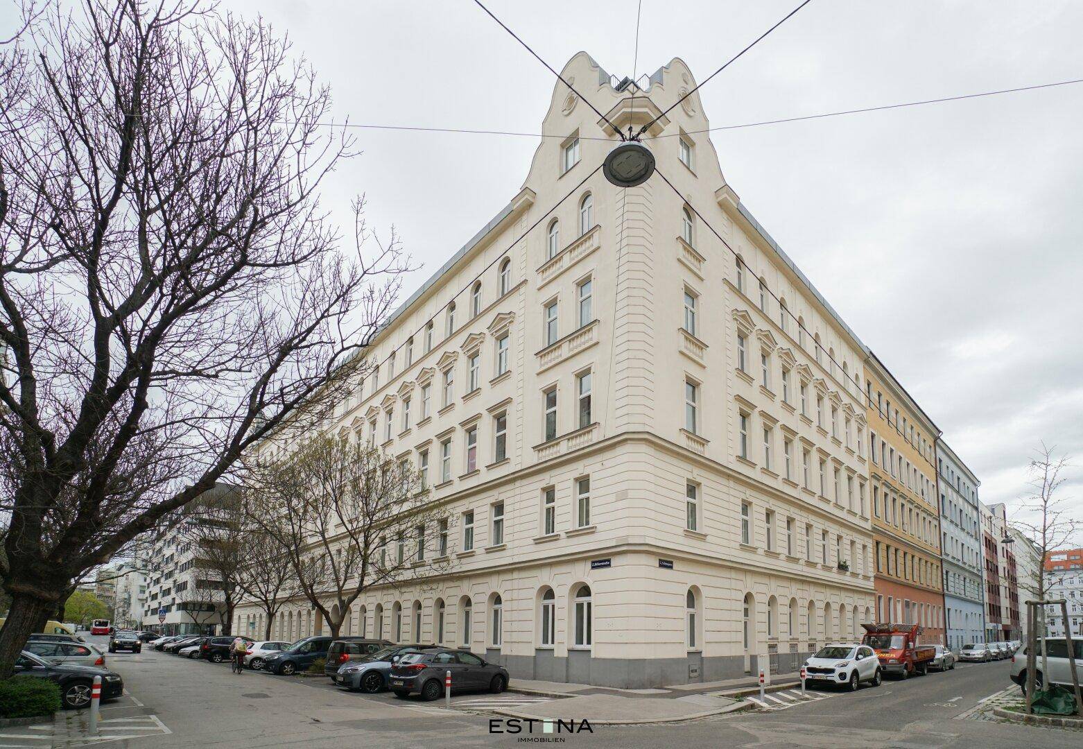 Großes Eckgebäude mit klassischer Architektur und vielen Fenstern an einer städtischen Straße.