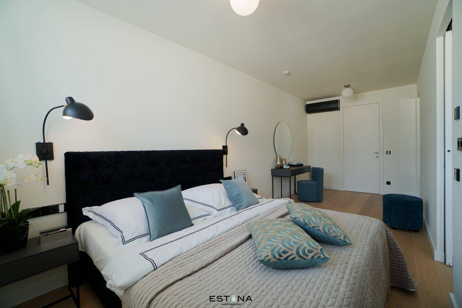 Modernes Schlafzimmer mit großem Bett, Holzboden, Schminktisch und einer Klimaanlage an der Wand.