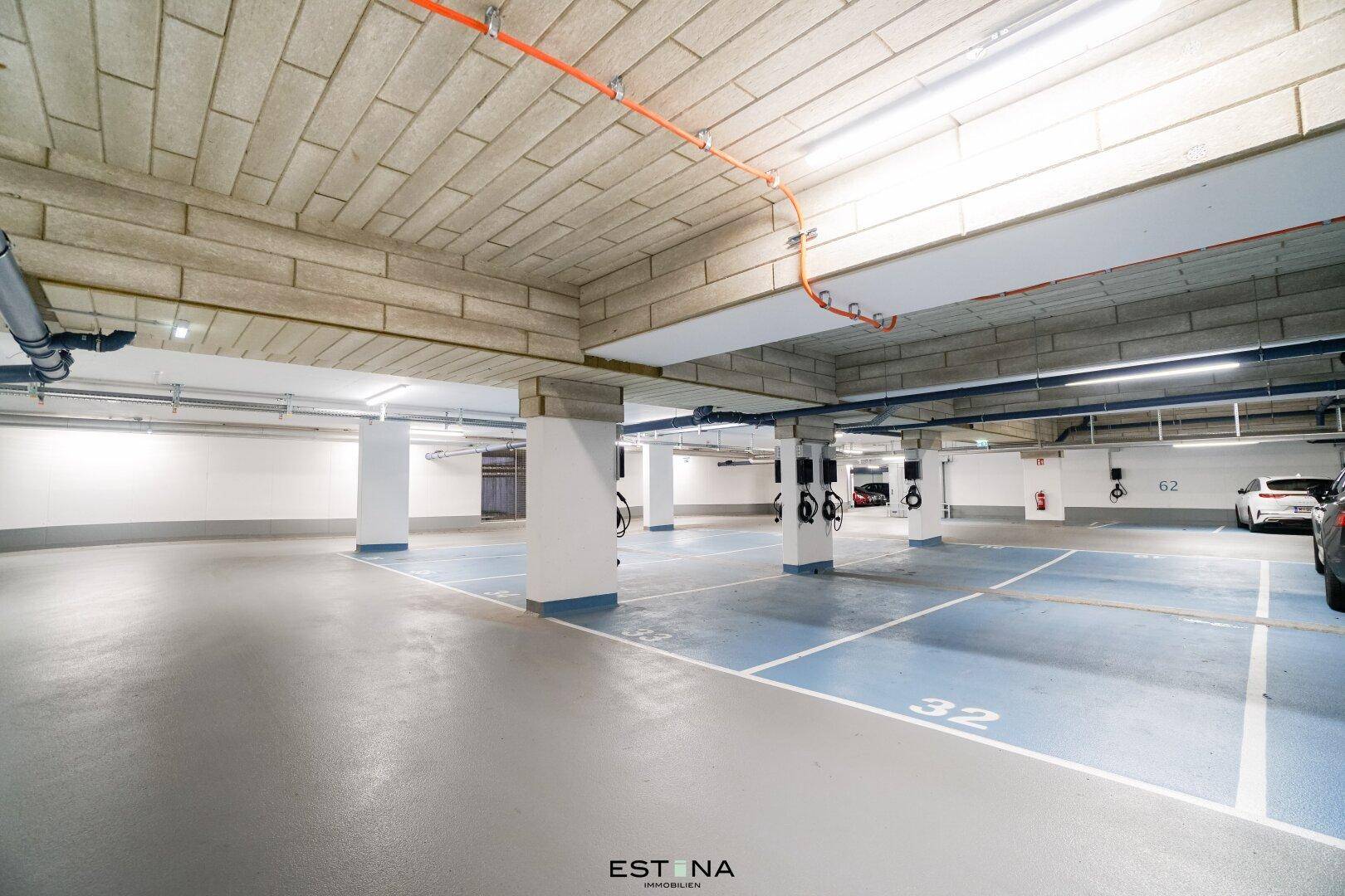Helle Tiefgarage mit zahlreichen Stellplätzen und Ladestationen für Elektrofahrzeuge.