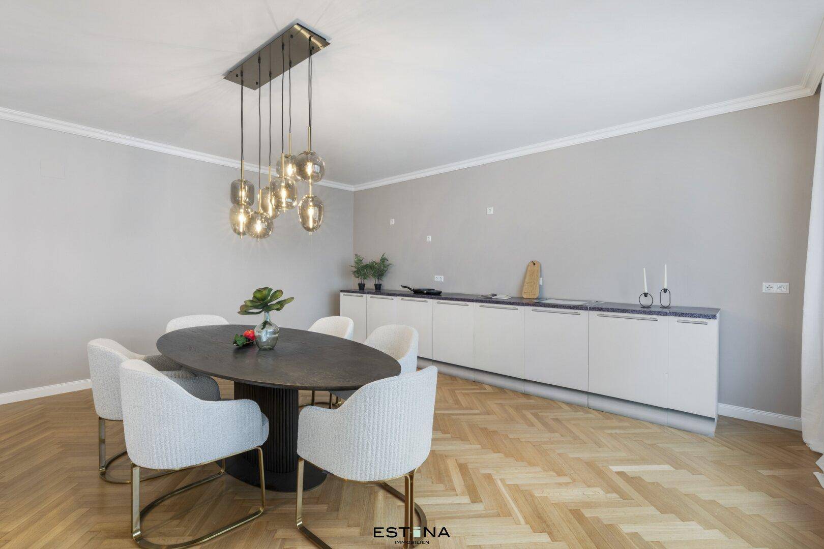 Eleganter Essbereich mit ovalem Tisch, modernen Stühlen und Fischgrätparkettboden.