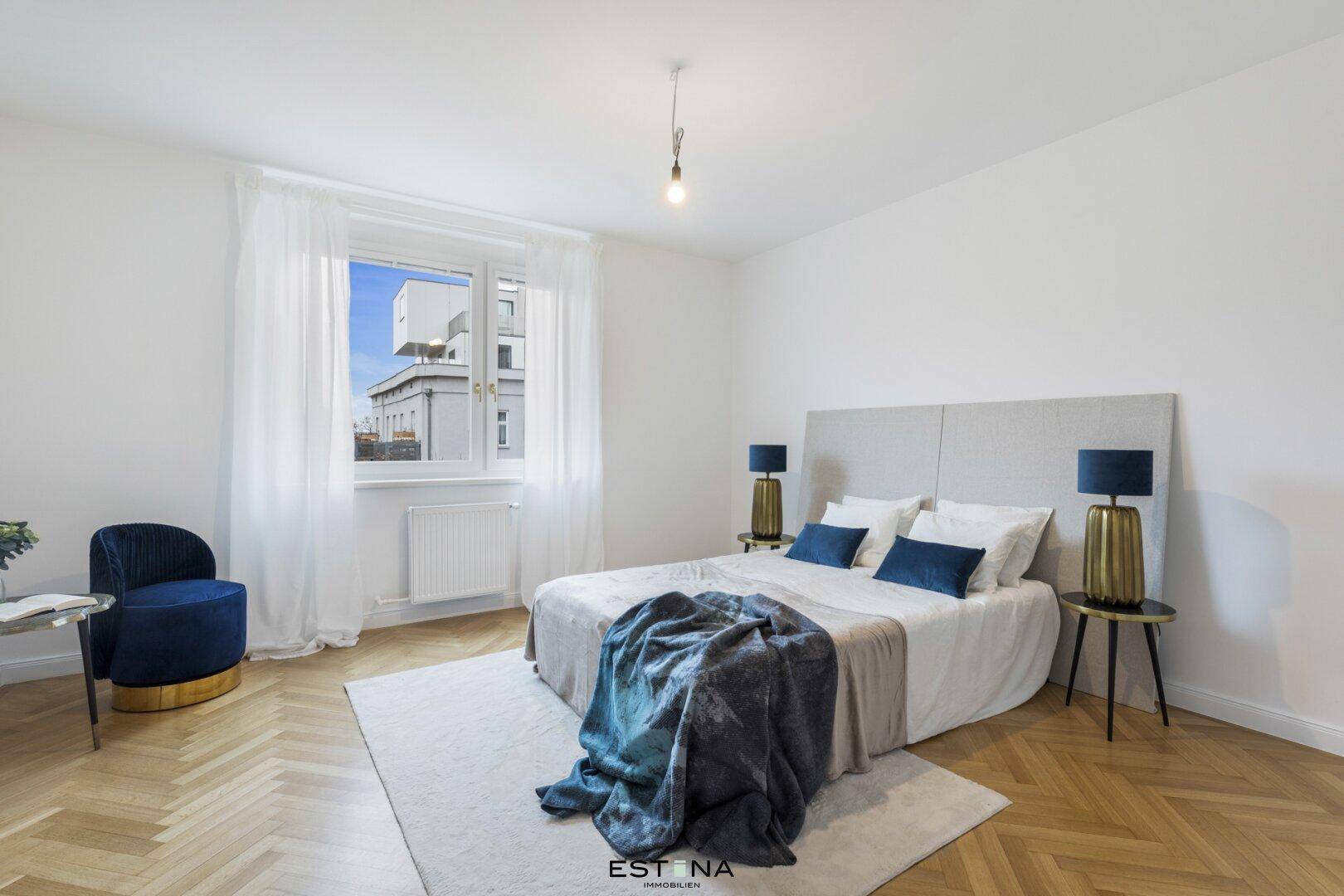 Geräumiges Schlafzimmer mit Doppelbett, blauen Akzenten und Fischgrätparkettboden.