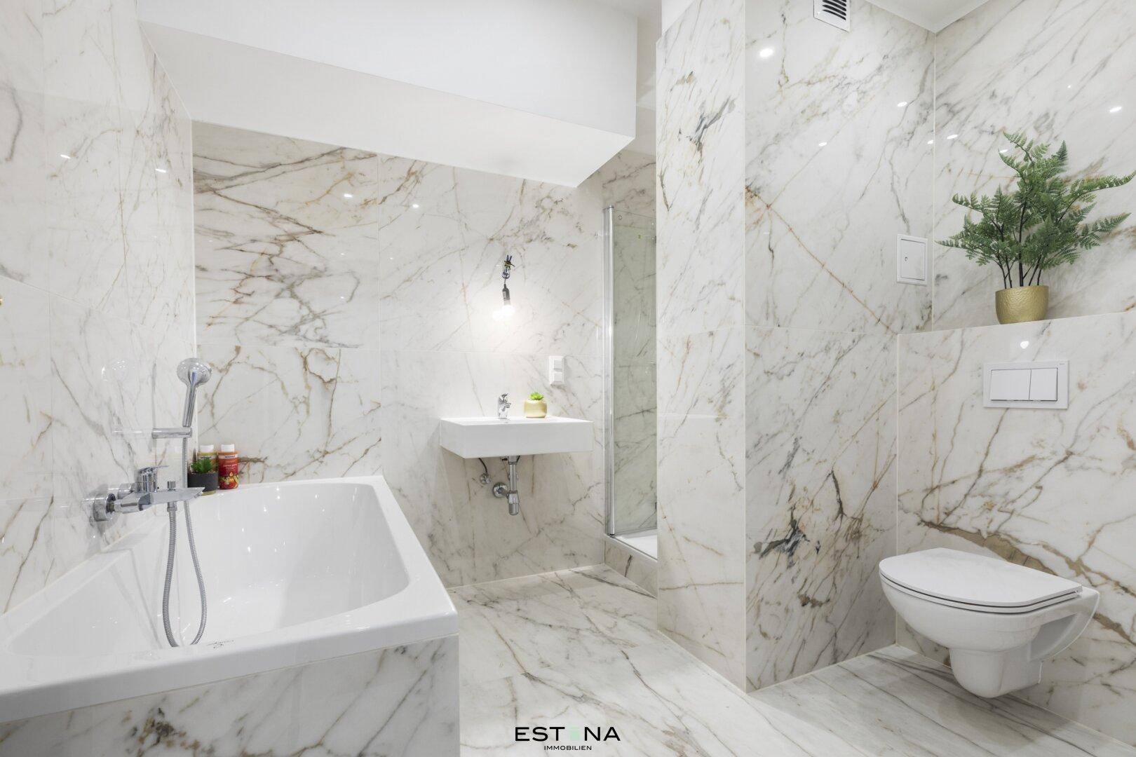 Luxuriöses Badezimmer mit Marmorfliesen, Badewanne und separater Dusche.