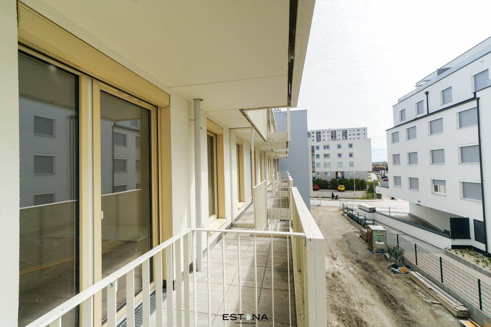 Langer Balkon mit Fliesenboden und Blick auf die umliegenden Neubauten und Baustellen.